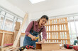 © godji10 - Selective Focus. Injuries and Accidents on female carpenter uses a hammer to hammering her finger at the carpentry shop. Handywoman apprentice working in workshop. DIY wood crafts and Hobby concepts.