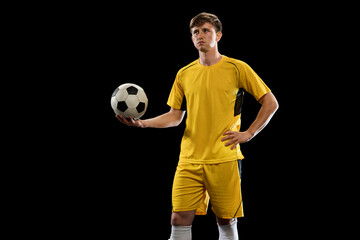 Wall Mural - Portrait of young soccer football player posing isolated on black background.