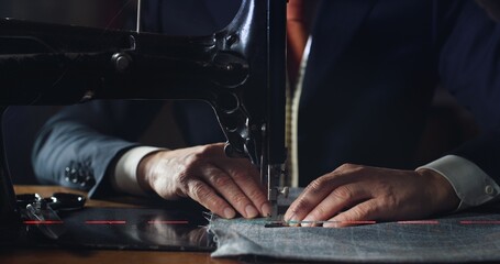 Close up shot of experienced tailor is sewing custom handmade high quality apparel in ancient luxury traditional tailoring workshop. Concept of industry, handmade, hand craft, couturier and tradition.