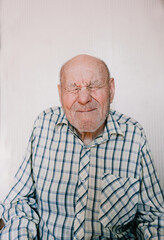 a large portrait of an old man on a light background with deep wrinkles, age spots.