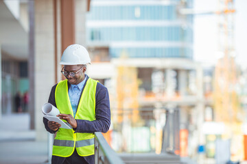 Business, building, industry, technology and people concept - Smiling builder in hardhat with tablet pc computer at construction site. Portrait of worker in a construction site