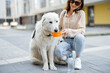 © rh2010 - Woman hold a bowl and gives a water to her big white dog while sitting on her feet in courtyard of the residence. Pet care, animal lover. Thirsty dog drinks water in hot summer