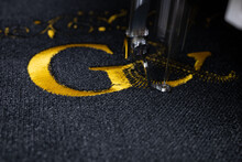 Machine Embroidery On Black Velvet Fabric With Yellow Thread. Embroidered Initial G. Close Up.