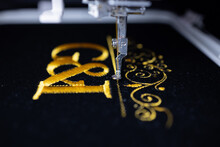 Machine Embroidery On Black Velvet Fabric With Yellow Thread. Embroidered Ornaments And Initials G And I. Close Up.