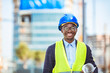 Close-up portrait of professional architect in hard hat looking at camera. Confident architect standing at construction site. Portrait of African American Engineer at a construction worksite.