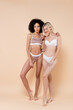 full length view of multiethnic women with perfect bodies posing in underwear on beige