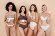 © LIGHTFIELD STUDIOS - slim interracial women holding cosmetic cream while posing in underwear on beige