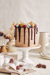 Canvas Print - Chocolate cake with intricate decorations and candies around it on a white wooden table