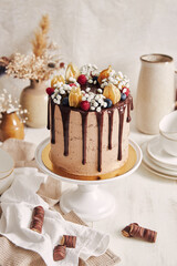 Sticker - High angle shot of a brown cake with dripping chocolate decorated with berries and flowers