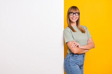 Portrait of lovely cheerful content minded girl looking at copy space placard isolated over bright yellow color background