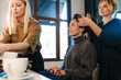 © Drobot Dean - Young two women doing hairstyle and makeup for their client
