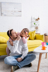 Wall Mural - father touching nose of cheerful daughter while playing prince and princess at home