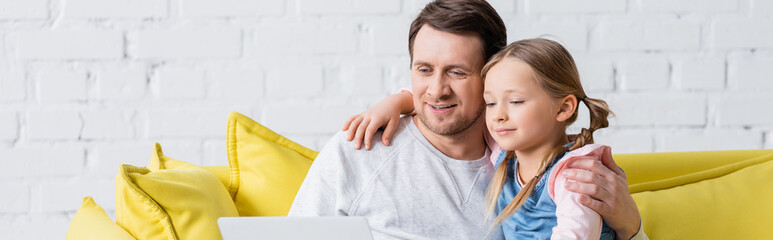 Wall Mural - happy dad with daughter watching movie on laptop, banner