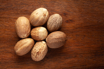 Wall Mural - Macro close-up of Organic nutmeg seed  (Myristica fragrans) on wooden top background. Pile of Indian Aromatic Spice. Top view