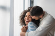 © LIGHTFIELD STUDIOS - cheerful multiethnic couple hugging at home