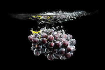 Wall Mural - Isolated Red grapes splashing and sinking in water on black