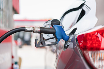 Car refueling with bule fuel nozzle at petrol station