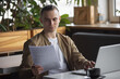 © antgor - Freelancer man working with papers and laptop PC in a cafe