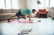 © Strelciuc - Blonde man is using a tablet while doing fitness exercises at home on a yoga mat
