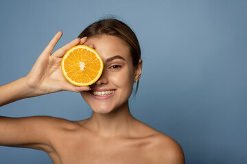 Wall Mural - Happy young woman holds citrus to her face. Vitamin c concept