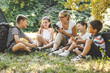 © BalanceFormCreative - Group of school kids sitting on grass in forest with they teacher.They learning about nature and wildlife.