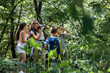 Group of children hiking in forest with they teacher.They're learning about nature and wildlife.Teacher using binoculars.	