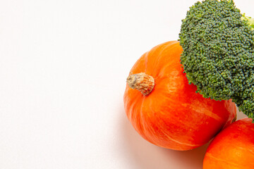 Creative layout of two orange pumpkins and broccoli on a white background. Food concept. Healthy eating. View from above. Copy space.