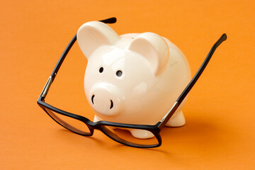 Wall Mural - Piggy bank and eyeglasses on the yellow background