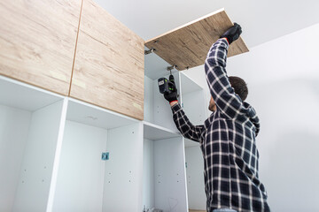 Wall Mural - The carpenter sets the door of the kitchen shelves