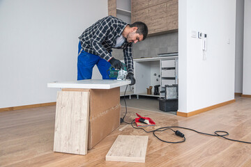 Wall Mural - A carpenter with a corded jigsaw cutting a part of the wooden surface (board)