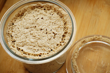 Homemade rye leaven in open glass jar top view on wooden table