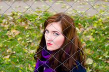 Portrait Of A Woman Behind A Metal Mesh On A Background Of Nature