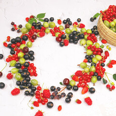 Wall Mural - Summer currants, raspberries and gooseberries lie in shape of heart on white background. Berries border design. Close up top view or flat lay with place for text.