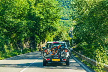 A passenger car is driving on the road, rear view, rear-attached bike