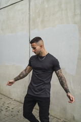 Canvas Print - Vertical shot of a sexy tattooed male in a street style outfit posing outdoors