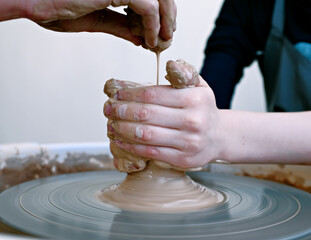 Teenage hands over the potter's wheel. Sculpt from clay in a pottery workshop. Traditional pottery craft. Ceramics workshop concept