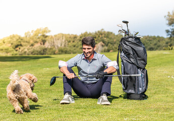 Poster - Young Caucasian male playing with his Goldendoodle dog on a professional golf course