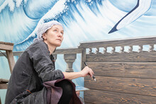 Mature Woman Artist Draws Thoughtful Looking At Her Work - A Mural On The Marine Theme