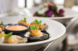 Selective focus shot of appetizing baked oysters with sauce served on a white plate