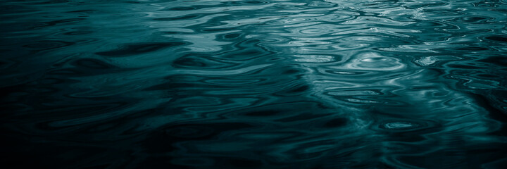 Wall Mural - Abstract dark blue green background. Reflection of sunlight on a wavy water surface. Beautiful teal background with copy space for design. Web banner.