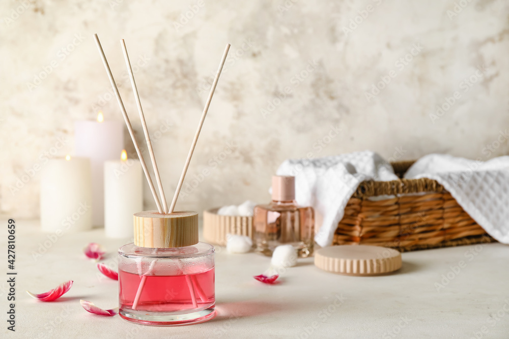 Reed diffuser with floral petals on light background
