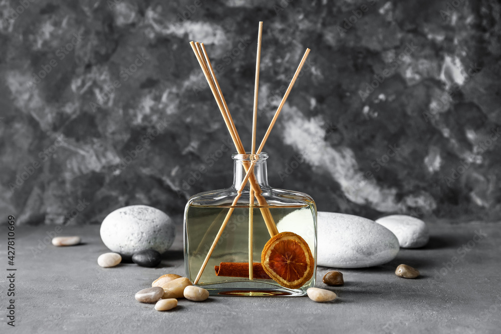 Reed diffuser with cinnamon, citrus and spa stones on grunge background