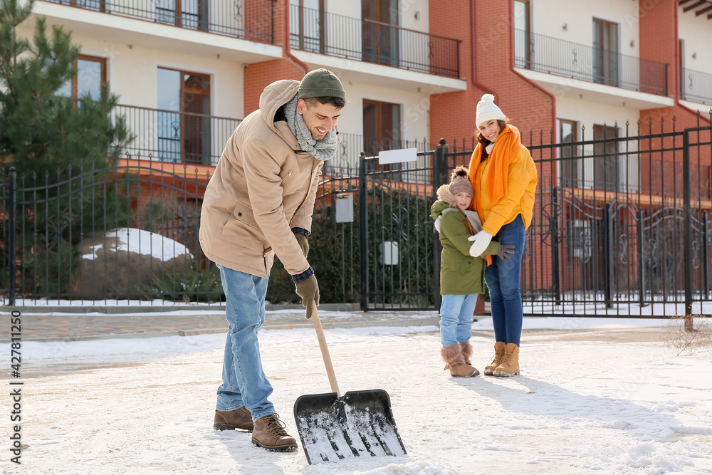 Family removing snow outdoors on winter day