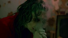 Horror Clown Woman Smokes In A Gloomy Room With Makeup On Her Face
