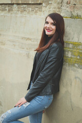 Sticker - Beautiful Caucasian female with red lipstick and leather coat leaned on a wall outdoors