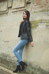 Sticker - Beautiful Caucasian female with red lipstick and leather coat leaned on a wall outdoors