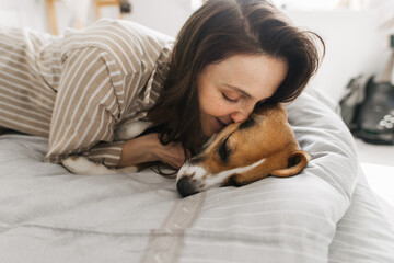 Wall Mural - young woman with a dog in bed having fun in the morning