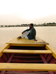 Sticker - man sitting on colorful wooden boat,evening view at head Saifan melsi Pakistan,