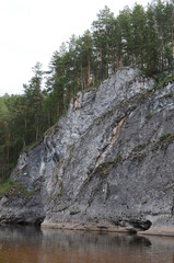 travel photography, rock with coniferous forest on the river coast on sky background closeup. Selective focus. 