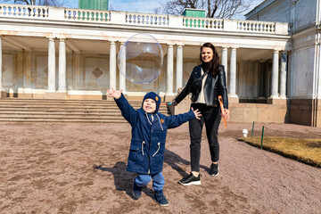 Russia. Saint Petersburg. Child playing with soap bubbles. Mother with her son.